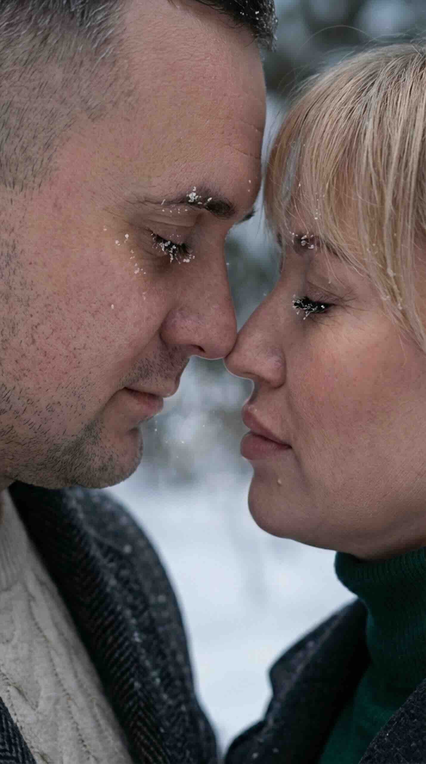Neural network photo: handsome man touching noses with a beautiful woman, snowflakes on eyelashes.